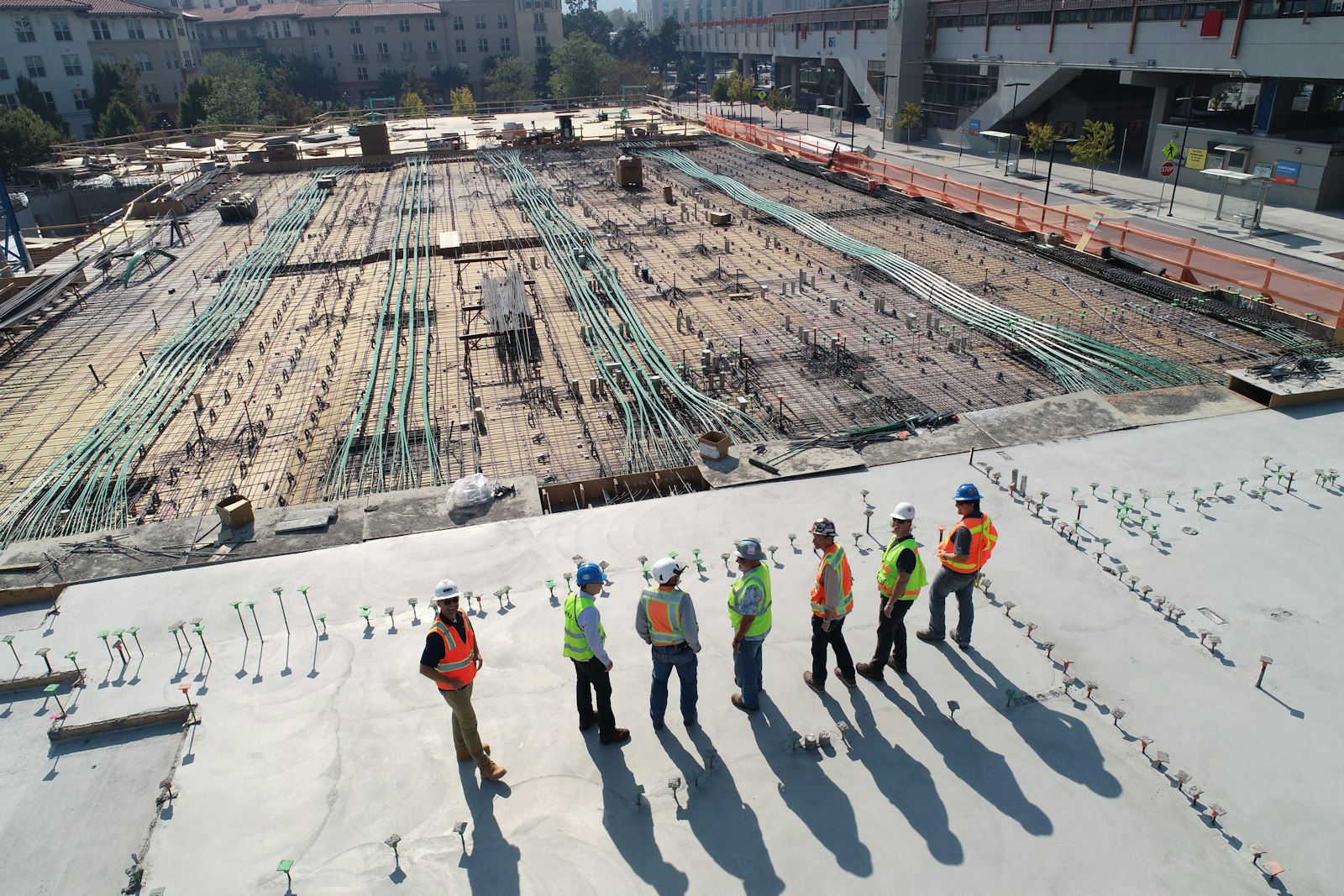 A crew of construction workers in high-visibility vests and hard hats on a job site