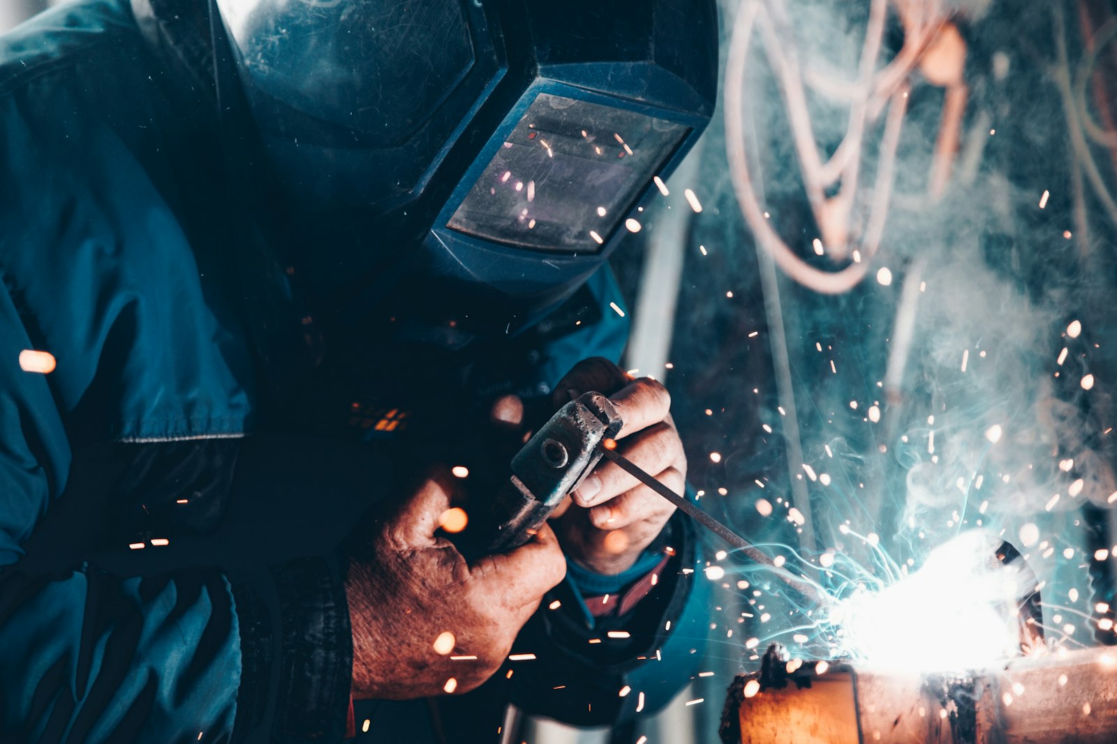 A welder at work in protective gear, sparks flying